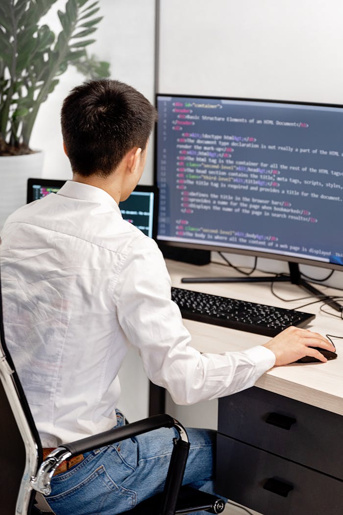 journey Back view of a programmer in a white shirt coding in an office workspace.
